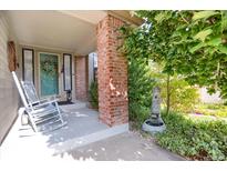 Charming front porch with rocking chairs, brick pillar, lovely landscaping and a decorative water feature at 6112 Alkire Ct, Arvada, CO 80004