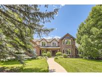 Charming brick and siding home featuring a landscaped front yard, mature trees, and inviting curb appeal at 4681 S Columbine Ct, Cherry Hills Village, CO 80113