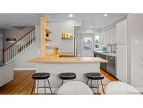 Bright kitchen boasts stainless steel appliances, white cabinets, and a butcher block breakfast bar with seating at 2867 Jasmine St, Denver, CO 80207