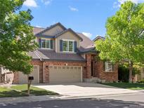 Charming two-story brick home featuring a tile roof, a three car garage, and mature trees at 11842 Altura St, Commerce City, CO 80603
