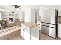 Modern kitchen with island, stainless steel refrigerator, hardwood floors, and an open design to living room at 11842 Altura St, Commerce City, CO 80603