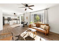 Open concept living room with hardwood floors, adjacent to kitchen with an eat-in dining set at 11842 Altura St, Commerce City, CO 80603