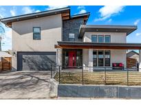 Contemporary two-story home featuring a bright red front door, a gray garage door, and a covered porch at 745 S Eliot St, Denver, CO 80219