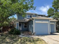 Charming two-story home with a blue exterior and attached one car garage at 897 Mockingbird Ln, Brighton, CO 80601