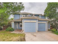 Two-story home features blue siding, beige trim, dual garages, and landscaping at 897 Mockingbird Ln, Brighton, CO 80601