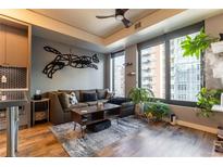 Bright living room featuring a comfortable couch, hardwood floors and modern decor and large windows with city views at 1750 Wewatta St # 705, Denver, CO 80202