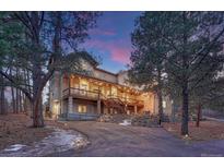 Stately multi-story home featuring an expansive wrap-around balcony and an illuminated driveway at 17015 Oxbridge Rd, Monument, CO 80132