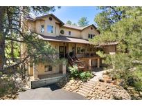 Charming two-story home with a covered porch and mature trees around the front yard at 17015 Oxbridge Rd, Monument, CO 80132