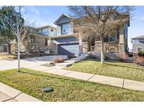 Charming two-story home featuring a stone-accented facade, covered porch and well-maintained lawn in a friendly neighborhood at 26890 E Roxbury Pl, Aurora, CO 80016