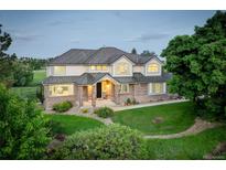 Beautiful two-story home featuring a brick facade, manicured lawn, and mature trees at 7400 S Genoa Cir, Centennial, CO 80016