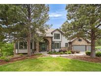 Stunning exterior view with a stone archway, stone accents, lush lawn, and mature trees on a sunny day at 920 Shady Oak Ln, Castle Pines, CO 80108