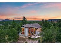 Modern home exterior featuring a patio, large windows, and natural surroundings at sunset at 8045 Eagle Rd, Larkspur, CO 80118