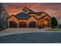 Stunning stucco home with a three-car garage, stone accents, and a covered entrance; warm lighting at dusk at 4337 W Hinsdale Ave, Littleton, CO 80128