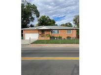 Brick ranch home with attached garage, well-manicured lawn, and chain link fence at 3515 Pierce St, Wheat Ridge, CO 80033