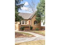 Charming brick home featuring a pathway leading to a vibrant red front door and manicured landscaping at 983 S Josephine St, Denver, CO 80209