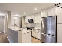 Bright kitchen with stainless steel appliances, white cabinetry, granite countertops, and a breakfast bar at 7455 E Quincy Ave # 103, Denver, CO 80237