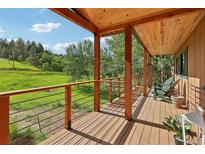 Inviting porch with wood ceiling offers views of lush, green landscape at 20033 Silver Ranch Rd, Conifer, CO 80433