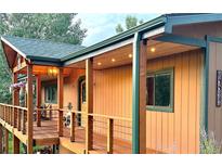 Outdoor porch with wood flooring, wooden beams, cable railings, hanging flower baskets, and exterior lighting at 20033 Silver Ranch Rd, Conifer, CO 80433