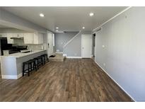 Open-concept living area with kitchen bar, wood floors, and neutral wall color provides flexible living at 2441 S Xanadu Way # A, Aurora, CO 80014