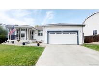 Charming home with a two-car garage, an American flag and a well-manicured lawn at 13871 Ivy St, Thornton, CO 80602