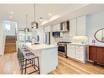 Modern kitchen with stainless appliances, island seating, and hardwood floors at 3880 W 13Th Ave, Denver, CO 80204