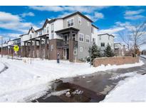 Modern townhomes featuring balconies with brick and gray siding, set against a snowy landscape and bright blue sky at 1312 Independence St # 3, Lakewood, CO 80215