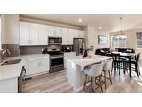 Modern kitchen features white cabinets, stainless steel appliances, and a central island with bar seating at 1312 Independence St # 3, Lakewood, CO 80215