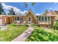 Charming brick home with a manicured lawn and inviting front porch with chairs at 879 S Cole Dr, Lakewood, CO 80228