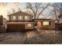 Charming two-story home with a brick and siding exterior, attached garage, and mature trees at 9556 W Maplewood Ave, Littleton, CO 80123