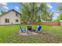 Spacious backyard featuring a fire pit with chairs and a large, mature tree providing ample shade at 32 Powder Horn Pl, Longmont, CO 80504