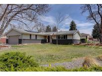 Charming single-story home with a well-maintained lawn and mature trees under a bright, blue sky at 6272 S Garfield Dr, Centennial, CO 80121