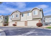 Tan three-unit townhouse building with attached garages and landscaping at 16083 E Geddes Dr # 73, Aurora, CO 80016