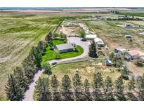 Aerial view of a sprawling farm with a well-maintained home, outbuildings, and fenced pastures, perfect for rural living at 50950 E 32Nd Ave, Bennett, CO 80102