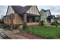 Charming two-story home featuring a classic brick facade, covered front porch, and a well-maintained lawn at 1653 Trenton St, Denver, CO 80220