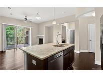 Modern kitchen features a granite island with a stainless steel sink and appliances at 303 Inverness Way # 201, Englewood, CO 80112