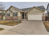 Charming single-Gathering home featuring a stone facade, well-manicured lawn, and a spacious two-car garage at 10968 Macon St, Commerce City, CO 80640