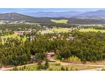 Expansive aerial view of a private home nestled in a lush forest with mountains in the distance at 25808 Sunrise Ln, Golden, CO 80401