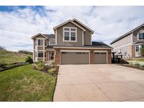 Charming two-story home with a three-car garage and well-manicured lawn and blue sky at 1076 Switch Grass Dr, Castle Rock, CO 80109
