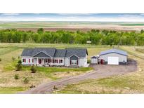 Charming ranch-style house with red shutters and a spacious workshop, nestled in a serene country setting at 196 W 8Th Ave, Byers, CO 80103