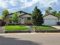 Charming brick home with a well-manicured front yard and a detached two-car garage at 10949 E 109Th Pl, Northglenn, CO 80233