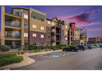 Beautiful apartment building with colorful architectural details and a well-maintained parking lot at dusk at 1044 Rockhurst Dr # 207, Highlands Ranch, CO 80129