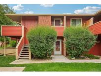 Charming townhouse with a red exterior, lush green bushes, and a welcoming front entrance at 1415 Bacchus Dr # D9, Lafayette, CO 80026