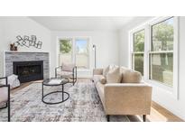 Bright living room features modern decor, a stylish fireplace, and large windows providing ample natural light at 2275 S Yosemite Cir, Denver, CO 80231