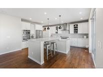 Bright, open kitchen with white cabinets, a large island, pendant lighting, and stainless steel appliances at 11023 Pastel Pt, Parker, CO 80134