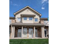 Charming condo building featuring a stone facade and well-manicured lawn under a sunny blue sky at 10818 Cimarron St # 206, Firestone, CO 80504