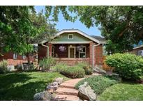 Charming brick home featuring a landscaped front yard with stone pathway and mature trees at 3622 Lowell Blvd, Denver, CO 80211