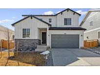 Two-story home featuring a gray garage door, stone accents, and white siding, blending modern charm with classic design elements at 4590 Boone Cir, Brighton, CO 80601