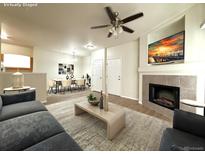 Cozy living room featuring a fireplace, ceiling fan, and view into the dining area at 4451 S Ammons St # 108, Littleton, CO 80123