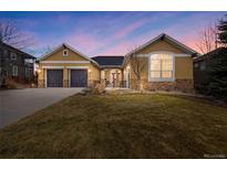 Charming stucco home featuring a two-car garage, stone accents, and a well-manicured lawn at 5118 Bottlebrush Run, Broomfield, CO 80023