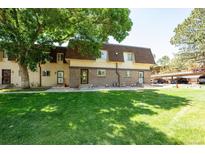 Inviting townhome exterior featuring a lush green lawn and classic brick accents at 7755 E Quincy Ave # T2, Denver, CO 80237
